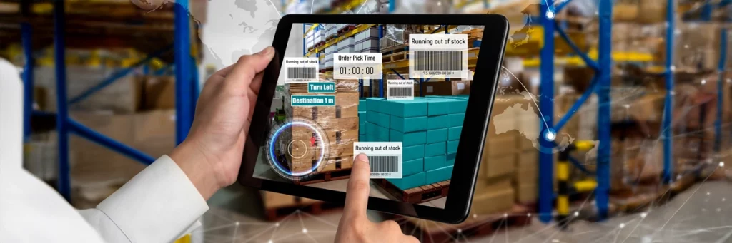 Person nutzt Tablet mit digitalen Monitoring-Tools und AR-Elementen zur Steuerung von Arbeitsprozessen in einer Werkhalle.